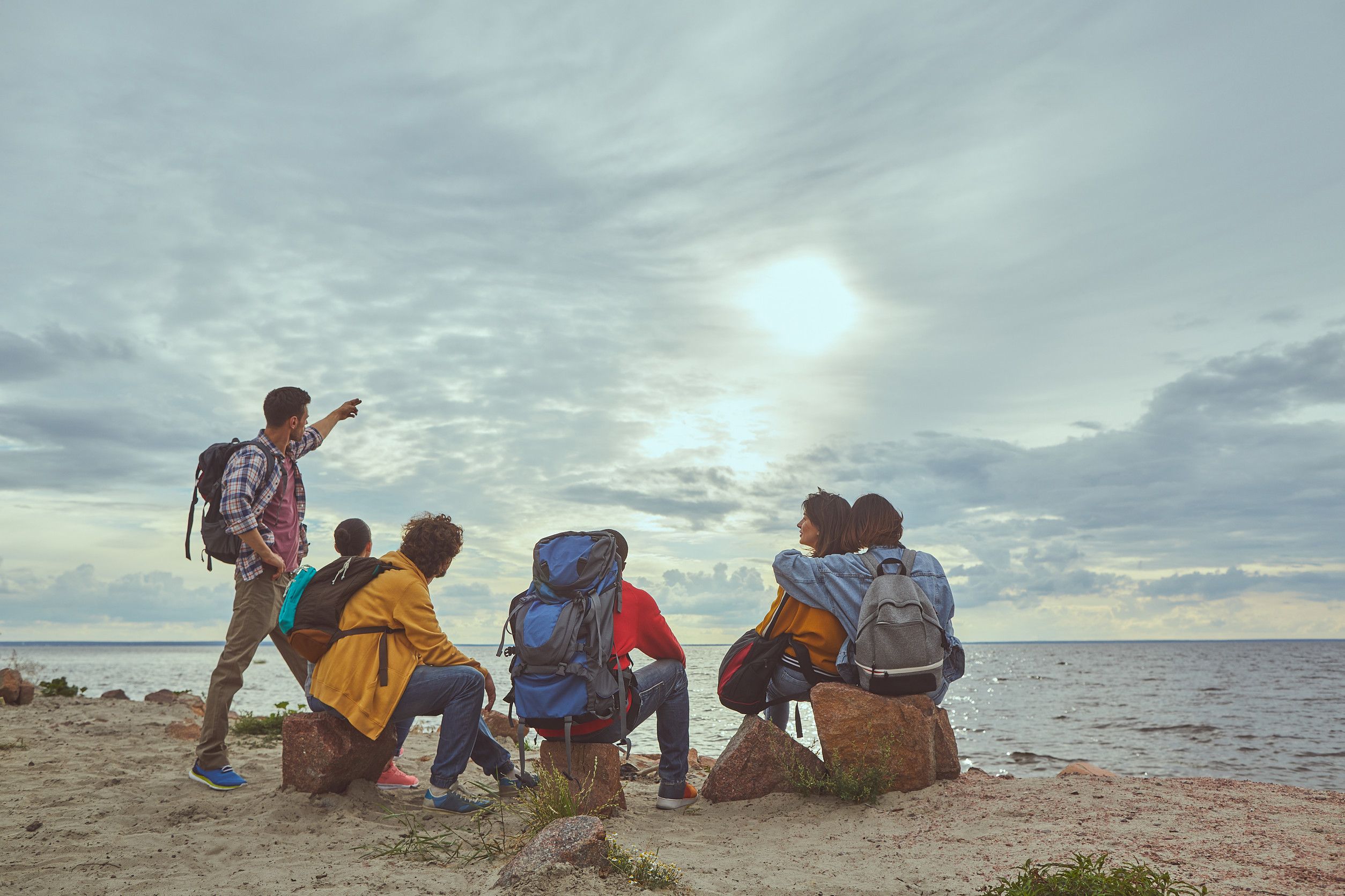 Moment Of Placidity Portrait Of Group Of Travelers Sitting At Seashore And Contemplating Splendid